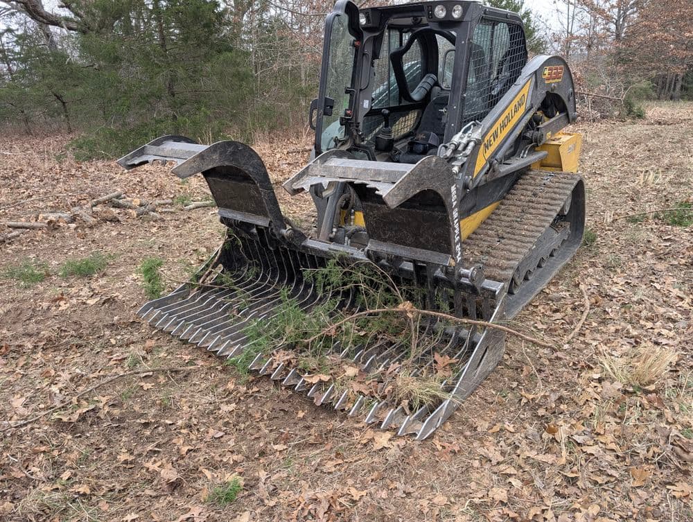 Bobcat with grapple attachment clearing brush in forested area, showcasing forest management.
